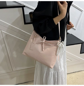 Detail der rosa Tasche mit Perlen-Spitzenanhänger und Lederschleife an der Schulter
