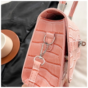 Detail of pink croc-embossed leather handbag showing silver hardware and side texture