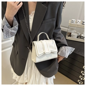 Detail of white mini crossbody bag with crocodile texture and metal chain strap