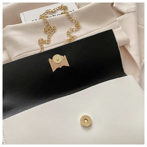 Detail of white leather envelope bag with gold chain strap and magnetic snap closure