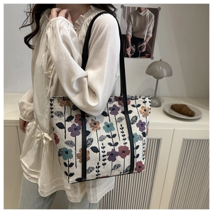 Detail view of woven floral canvas tote bag featuring vintage flower patterns and black handles