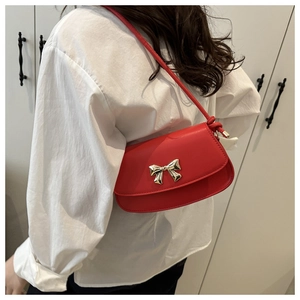 Détail du sac à bandoulière en similicuir rouge avec boucle nœud doré sur mannequin