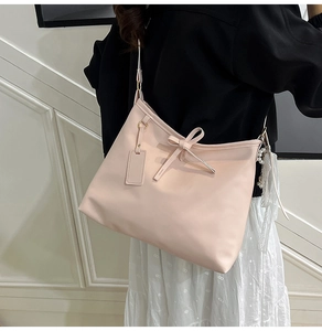 Close-up of a pink tote bag featuring a bow charm and smooth matte faux leather texture