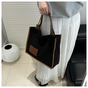 Detail of black corduroy tote bag with brown trim and stylish leather patch detail