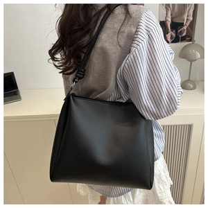 Detail of black large tote bag featuring a decorative knot design on the shoulder strap
