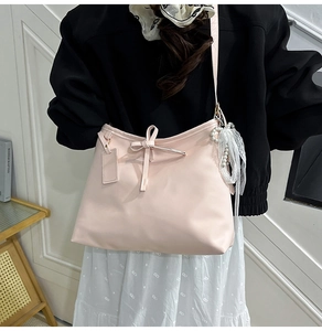 Detail of light pink tote bag featuring a bow decoration and pearl lace charm
