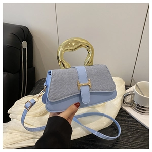 Detail of trendy box bag showing denim texture flap and gold H-buckle with metal handle