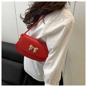 Détail du sac à bandoulière en similicuir rouge avec un nœud décoratif doré chic