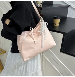 Détail du cabas rose clair avec nœud en cuir et décoration pendentif perle et dentelle