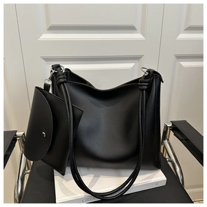 Detail of black textured tote bag with a knotted strap and matching mini pouch