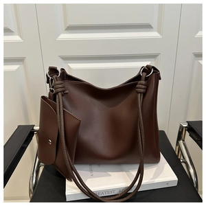 Macro detail of dark brown synthetic leather tote bag with knotted strap and small pouch