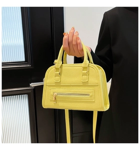 Detail of bright yellow boston bag showing litchi grain texture and metal zipper