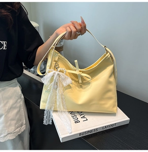 Detail of light yellow tote bag with white lace bow and pearl heart pendant
