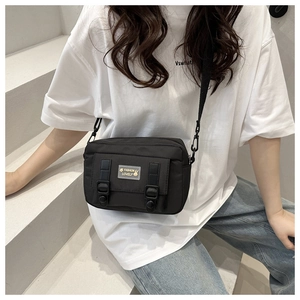 Detail van zwarte nylon crossbody tas met dubbele gespen en verstelbare schouderriem