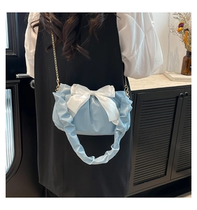 Detail of light blue pleated bag with large cream bow and gold metal chain strap