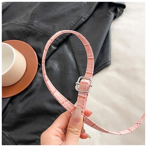 Detail of pink crocodile embossed leather strap with adjustable silver metal buckle