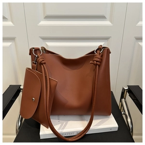 Detail of a brown leather tote bag showing the stylish knotted strap and mini pouch