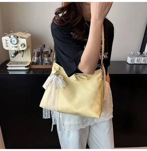 Close-up of yellow hobo shoulder bag with pearl bow accessory in a cozy cafe setting