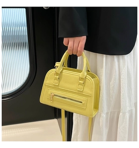 Detail of yellow lychee leather handbag with metal zipper and dual top handles