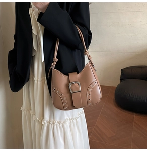 Close-up of caramel leather underarm bag with silver buckle and metallic eyelet details