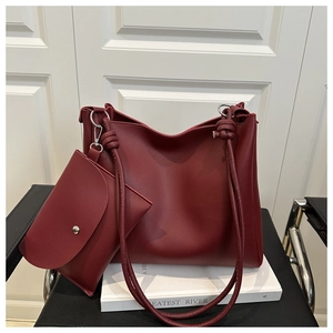 Detail of burgundy textured leather tote bag with shoulder strap knot and mini pouch