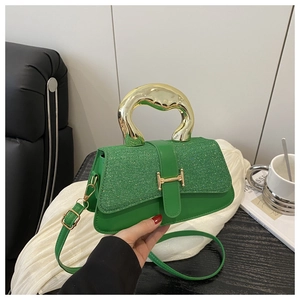 Close-up of green handbag with textured fabric, golden H-shaped clasp, and metal handle