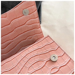 Detail of pink crocodile embossed leather bag showing a silver magnetic snap closure