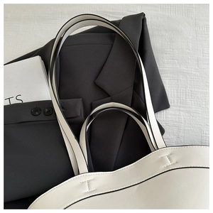 Detail of a white minimalist tote bag with black trim and decorative I-stitching