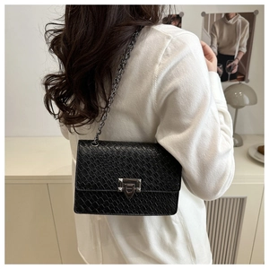 Close-up of black crocodile pattern leather bag with silver metal chain and lock buckle
