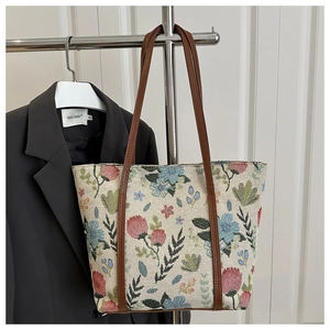 Detail of vintage floral jacquard tote bag with dark brown leather handles on display