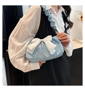 Detail of light blue pleated cloud bag with large white bow and ruffled shoulder strap