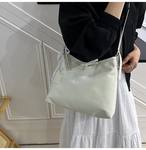 Détail du sac à main blanc avec nœud décoratif et élégant pendentif en perles et dentelle
