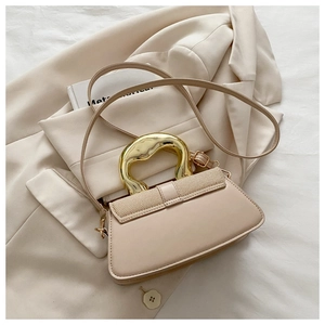 Close-up of beige crossbody bag featuring woven texture and unique gold metal handle