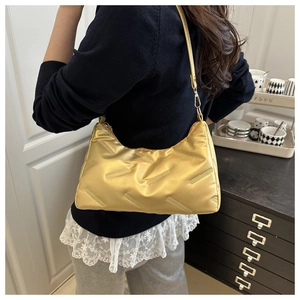 Modische goldene gesteppte Unterarmtasche an einem Model für einen stilvollen Look