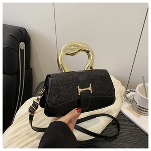 Detail of black crossbody bag featuring gold streamlined handle and textured metal buckle