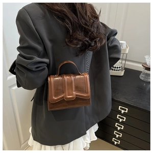 Detail of brown faux leather crossbody bag with stone pattern and metal chain strap