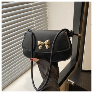 Détail du sac à bandoulière noir mat avec boucle nœud dorée et fine bandoulière