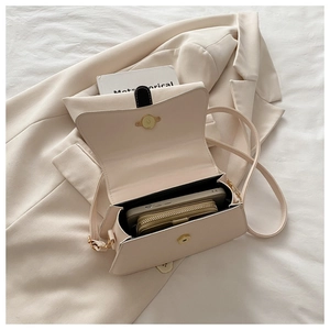Detail view of the beige crossbody bag interior holding a smartphone and wallet