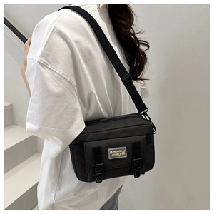 Detail van de zwarte nylon crossbodytas met verstelbare brede riem en schattig logo