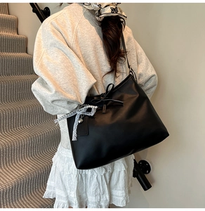 Detail of black PU leather tote bag with elegant pearl lace charm and bow decoration