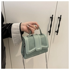 Détail d'un sac à main vert menthe en similicuir avec motif crocodile et chaîne argent
