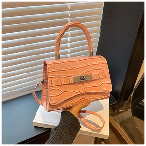 Detail of coral pink crocodile embossed leather texture with silver clasp on a small handbag