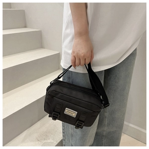 Detail van zwarte nylon crossbodytas met gespbanden en modieus logo-embleem