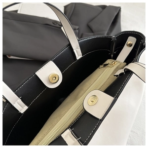 Detail shot of tote bag interior with gold zipper compartment and magnetic buckle closures