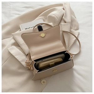 Interior view showing the capacity of this beige box bag with a phone and a small wallet