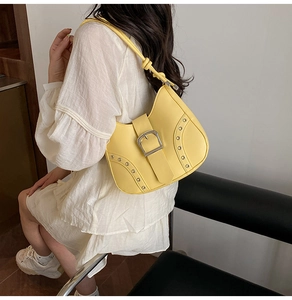 Detail of yellow crescent shoulder bag with silver buckle and eyelet metal accents