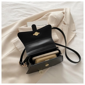 Detail view of black crossbody bag interior showing phone and gold zipper wallet capacity