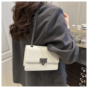 Detailed view of a white woven shoulder bag with dark metal chain strap and retro clasp