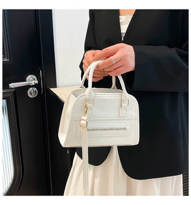 Detail of white lychee leather Boston bag featuring gold-tone hardware and dual handles