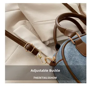 Close-up of golden metal adjustment buckle on blue denim bag with leather trim